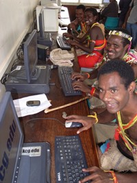 民族衣装を着けてKCGから寄贈されたパソコンを操作するパプアニューギニア・ゴロカ大学の学生