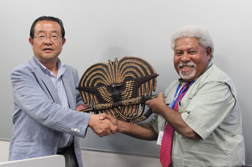 パプアニューギニア教育省マダコ・スワリ氏からプレゼントを寄贈される寺下KCGI副学長