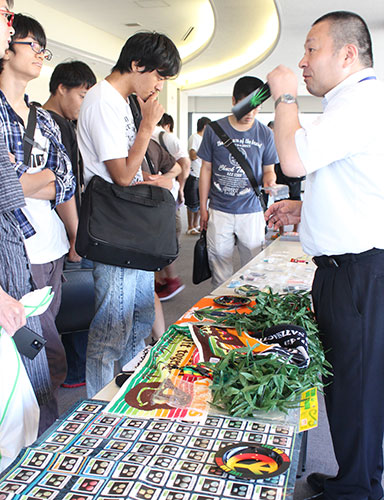 薬物乱用防止についての講演後，グッズを展示して学生たちの質問に答える京都府警本部組織犯罪対策第3課 警部補の辻 健さん（右）