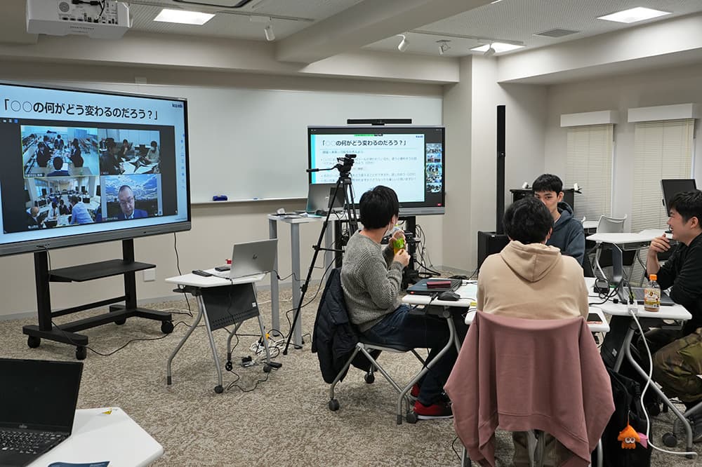 KCGと京都府立京都すばる高等学校，三重県立亀山高等学校の3校により遠隔講義システムを使って実施された実証授業。グループワークで学生・生徒たちは，現在関心が高まっている生成AIについて話し合いました（2023年12月26日，KCGI百万遍キャンパスのハイフレックス仕様教室）