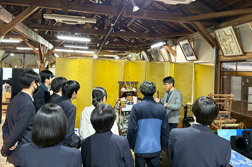 外装に甲冑を使用した等身大の2足歩行ロボット「キヨモリ」の説明を聞く生徒たち