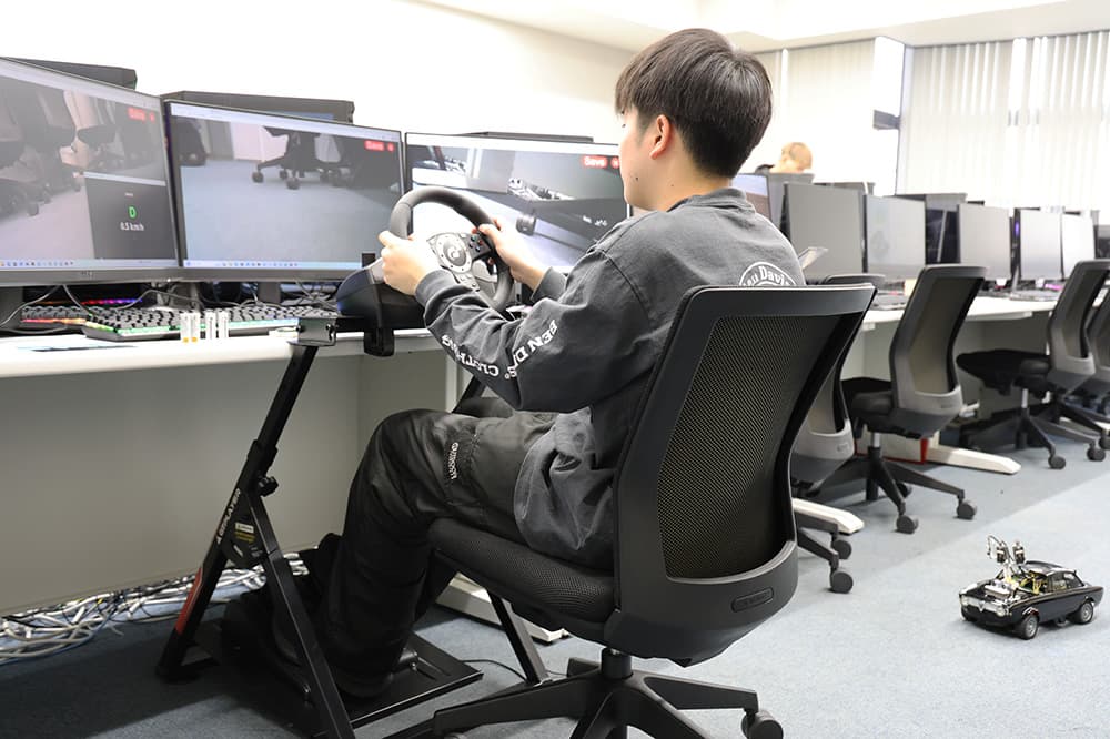 「自動運転シミュレータ」は無線通信で制御する自動車型ラジコンで，実際に車を運転しているような体験ができます（同，KCG京都駅前校）